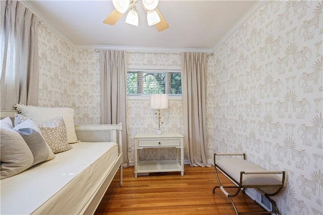 bedroom featuring wallpapered walls, ceiling fan, ornamental molding, and wood finished floors