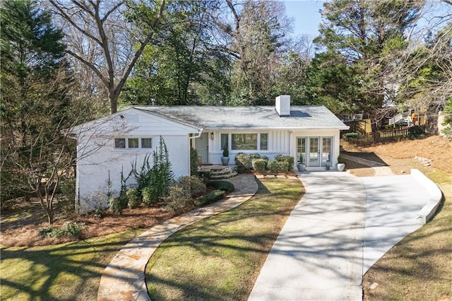 view of front of home featuring board and batten siding, a chimney, fence, and concrete driveway