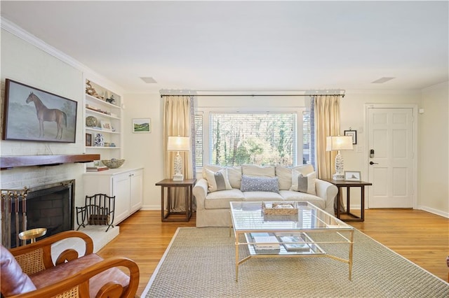 living room with a fireplace with raised hearth, crown molding, light wood-style flooring, and baseboards