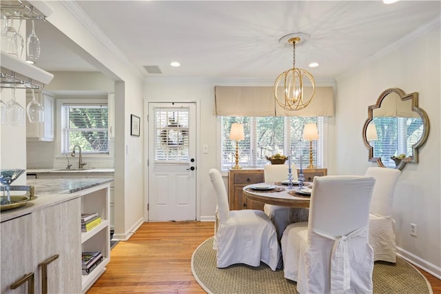 dining space with light wood finished floors, baseboards, ornamental molding, and an inviting chandelier