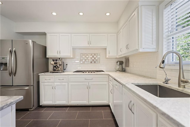 kitchen with white cabinetry, appliances with stainless steel finishes, decorative backsplash, and a sink