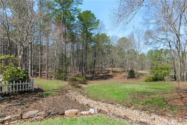 view of yard with a forest view and fence