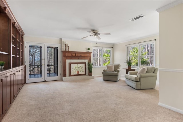 carpeted living room with visible vents, baseboards, ceiling fan, and crown molding