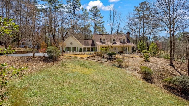 rear view of house featuring a lawn, covered porch, and a chimney