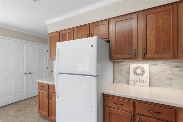 kitchen featuring brown cabinets, crown molding, and freestanding refrigerator