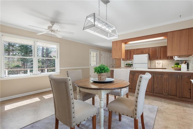 dining space featuring baseboards, ceiling fan, and crown molding