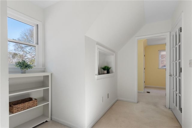 hall with vaulted ceiling, carpet flooring, baseboards, and a wealth of natural light