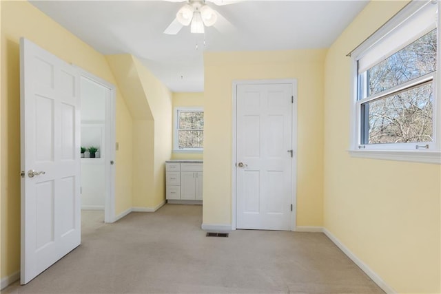 unfurnished bedroom featuring a ceiling fan, visible vents, baseboards, and light carpet