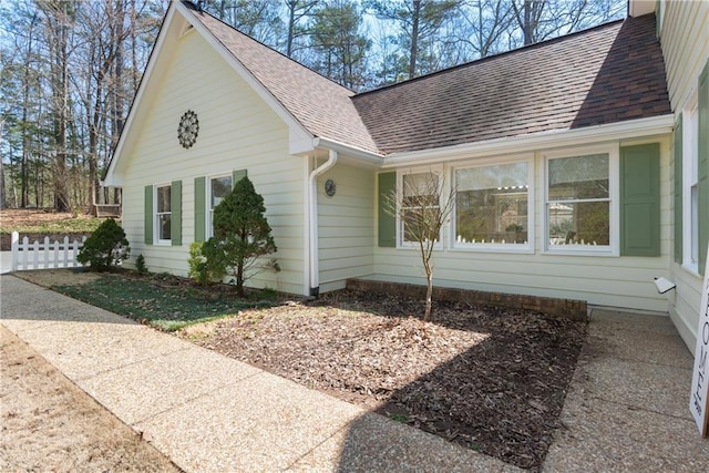 view of side of home with roof with shingles