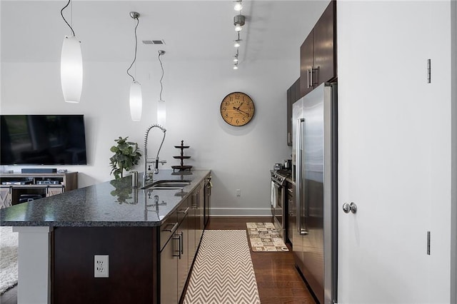 kitchen with high end fridge, sink, decorative light fixtures, and dark brown cabinetry