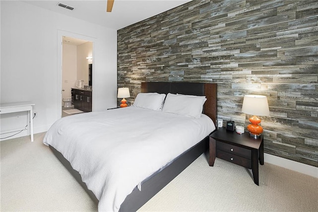 bedroom featuring ensuite bathroom, light carpet, and ceiling fan