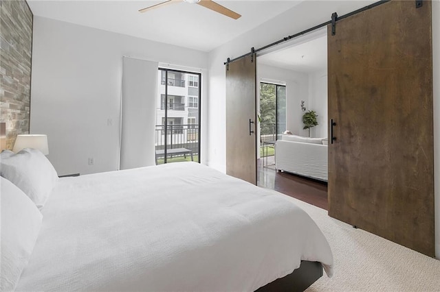 bedroom featuring a barn door, access to exterior, and ceiling fan