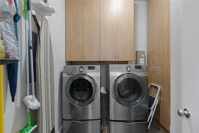 clothes washing area featuring cabinets and independent washer and dryer