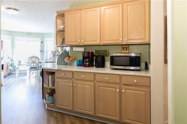 kitchen with decorative light fixtures, dark wood-type flooring, light brown cabinetry, a textured ceiling, and sink