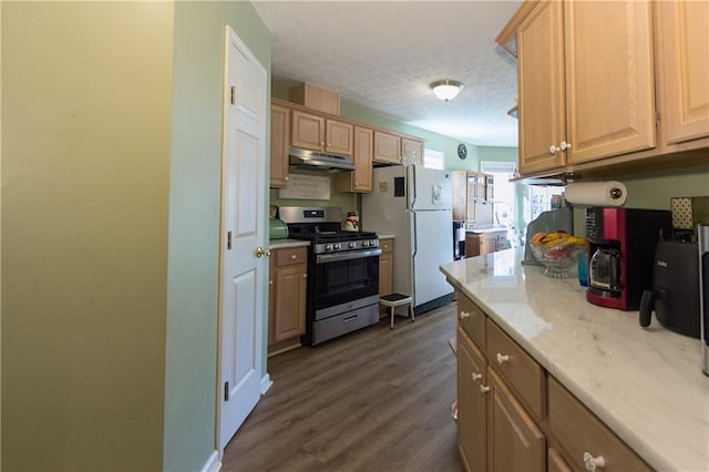 kitchen with a textured ceiling, dark wood-type flooring, light brown cabinets, white fridge, and stainless steel gas stove