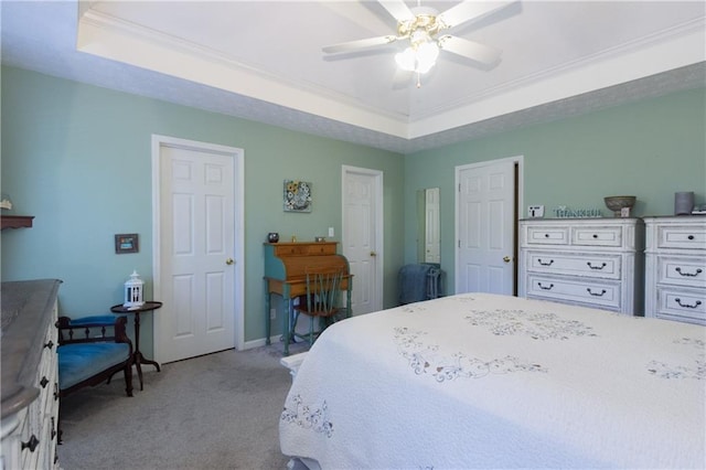 carpeted bedroom with ceiling fan, ornamental molding, and a raised ceiling