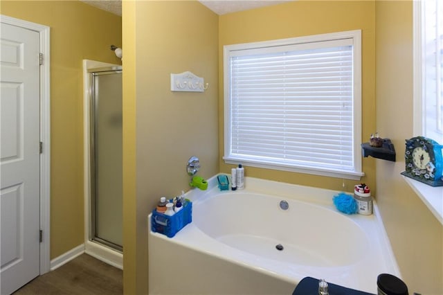 bathroom with wood-type flooring, a textured ceiling, and shower with separate bathtub