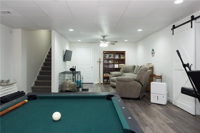 rec room with dark wood-type flooring, a paneled ceiling, ceiling fan, pool table, and a barn door