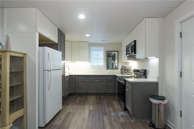 kitchen with appliances with stainless steel finishes, gray cabinetry, dark hardwood / wood-style floors, a drop ceiling, and sink