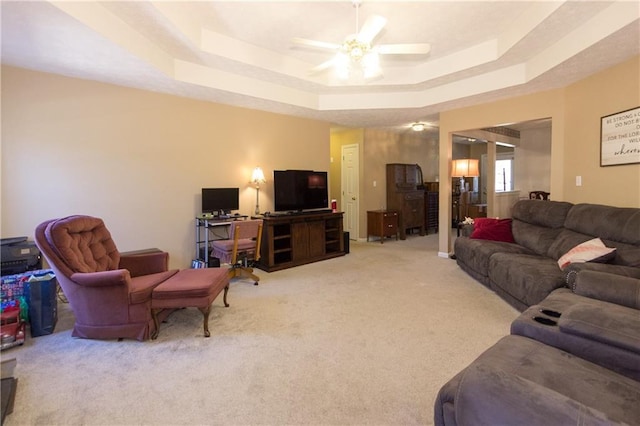 carpeted living room featuring ceiling fan and a tray ceiling