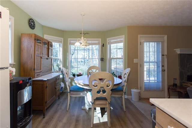 dining area with a textured ceiling, hardwood / wood-style flooring, and a notable chandelier