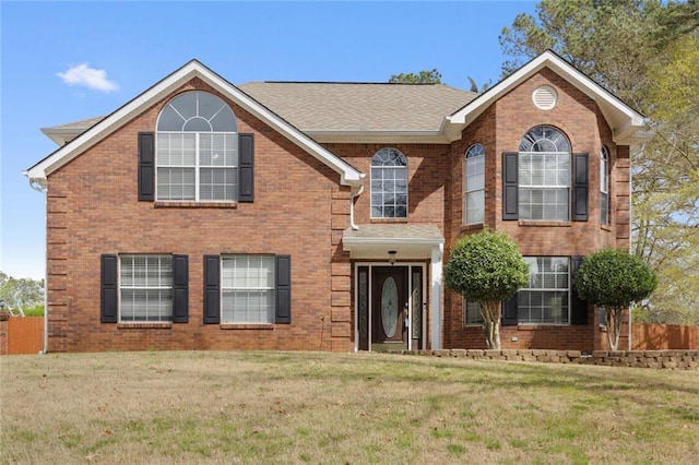 view of front of home featuring a front yard, fence, and brick siding