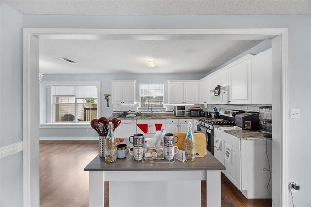 kitchen featuring dark wood-style flooring, dark countertops, white appliances, and white cabinetry