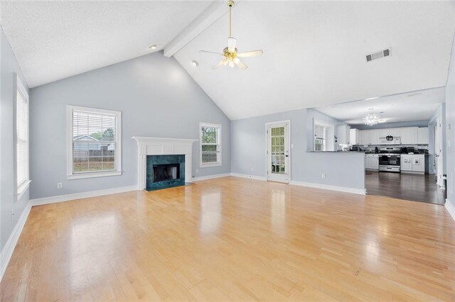 unfurnished living room featuring a healthy amount of sunlight, visible vents, ceiling fan with notable chandelier, and a fireplace