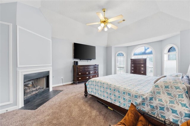 carpeted bedroom featuring a fireplace with flush hearth, visible vents, vaulted ceiling, and multiple windows