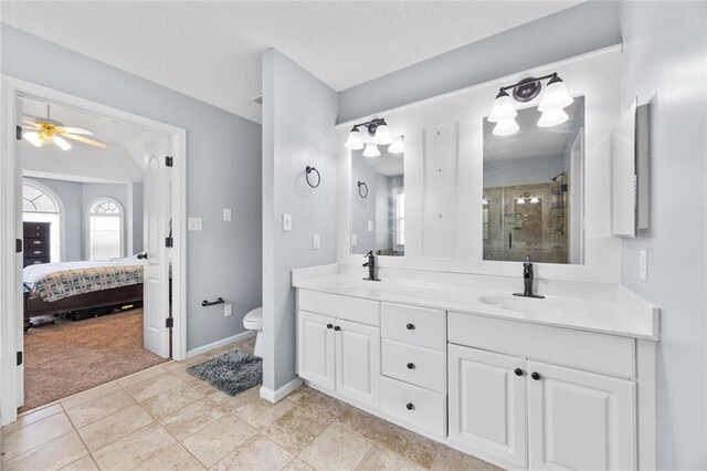 bathroom with toilet, a stall shower, double vanity, and a sink