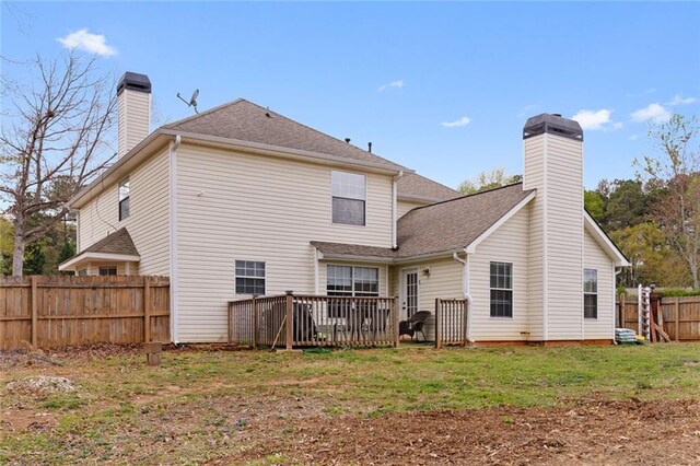 back of property with a chimney, fence, a yard, and roof with shingles
