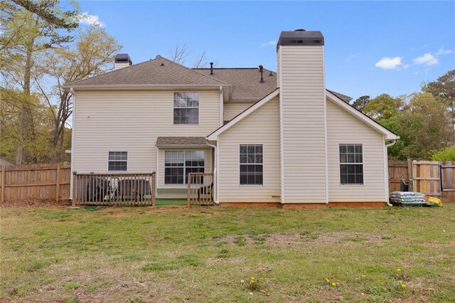 back of house with a chimney, a fenced backyard, and a lawn