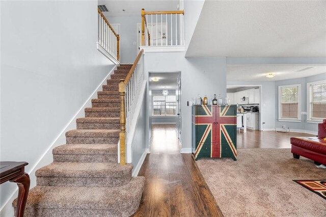 staircase featuring visible vents, wood finished floors, and baseboards