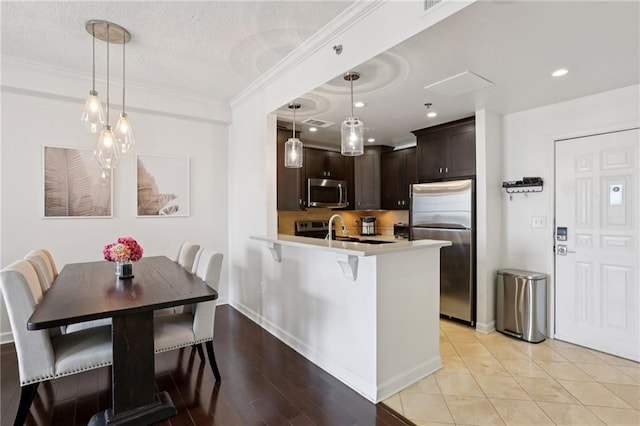 1101 Juniper St NE Unit 1012, Atlanta, GA 30309 - kitchen featuring stainless steel appliances, dark brown cabinets, light countertops, a peninsula, and tasteful backsplash