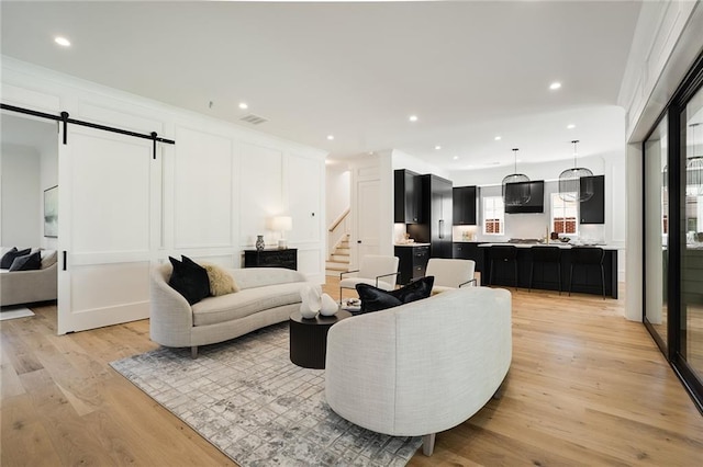 living room with a barn door and light hardwood / wood-style floors