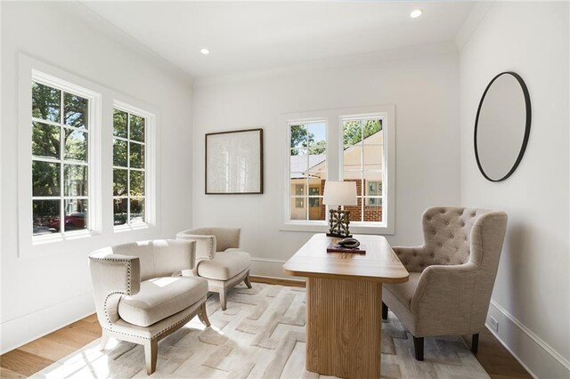 living area featuring crown molding and light hardwood / wood-style floors