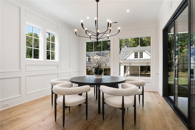 dining space with light hardwood / wood-style flooring and an inviting chandelier