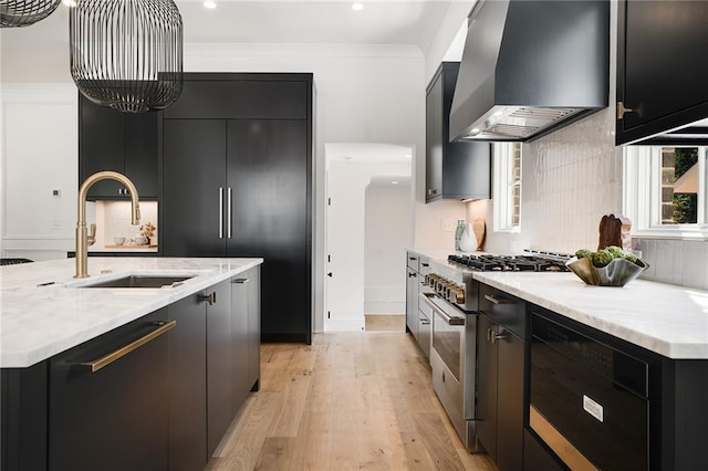 kitchen featuring sink, wall chimney range hood, an island with sink, and stainless steel appliances