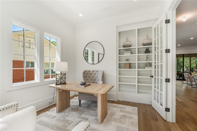 office area with wood-type flooring, ornamental molding, french doors, and a healthy amount of sunlight