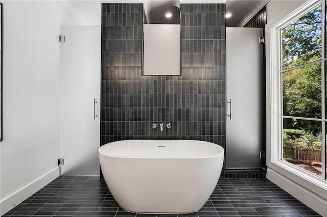 bathroom featuring a bath, tile patterned floors, and tile walls