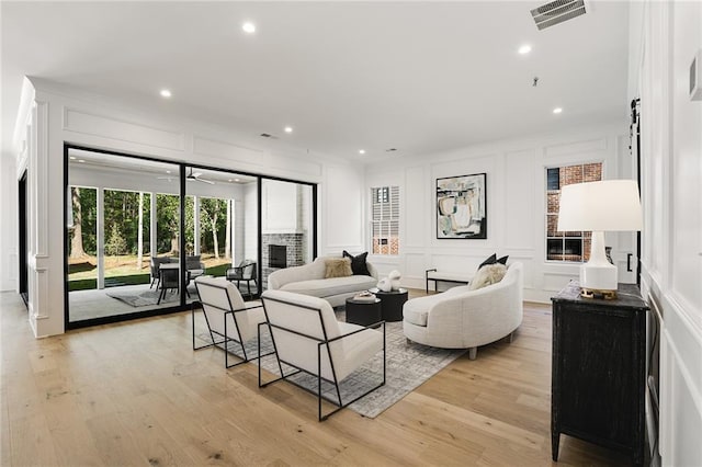 living room featuring light hardwood / wood-style flooring and a brick fireplace