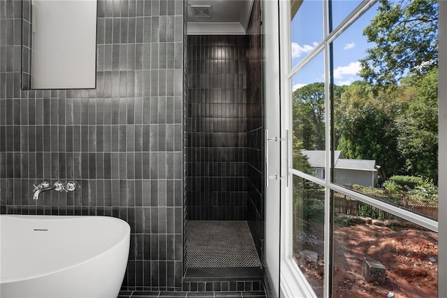 bathroom with tile patterned floors, a tub, and tile walls