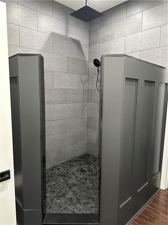 full bathroom with a tile shower and wood finished floors