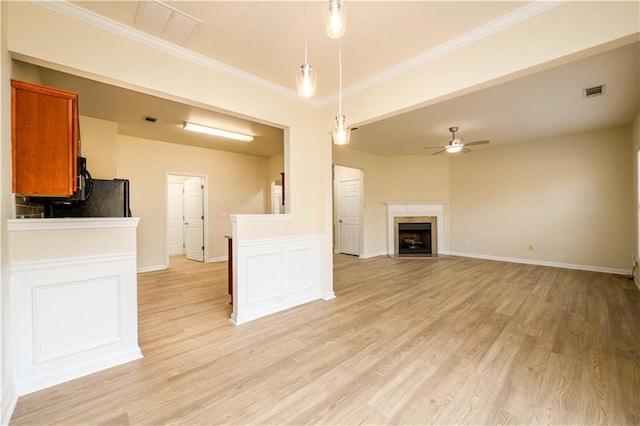 unfurnished living room with light wood finished floors, a ceiling fan, and ornamental molding