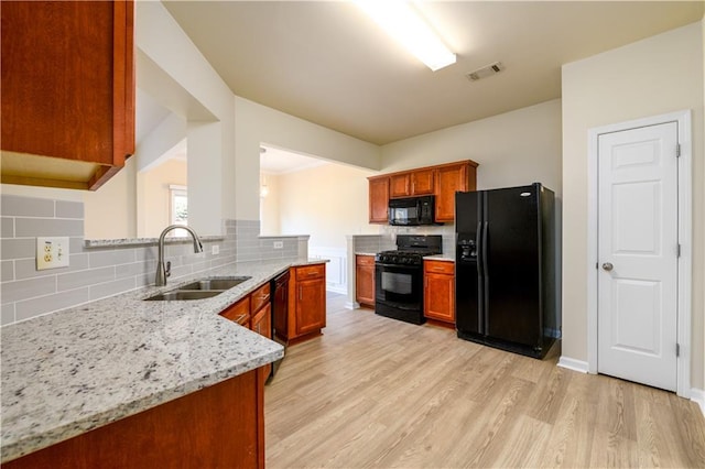 kitchen featuring visible vents, a sink, decorative backsplash, black appliances, and light wood-style floors