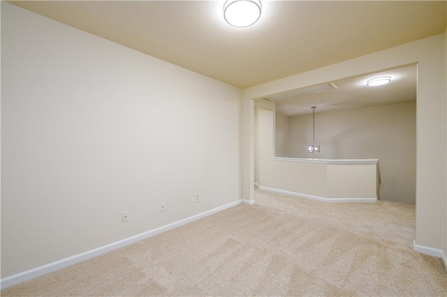 carpeted spare room featuring baseboards and attic access