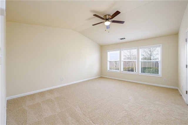 unfurnished room featuring visible vents, lofted ceiling, light colored carpet, and a ceiling fan