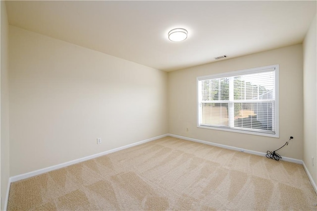 empty room with visible vents, light colored carpet, and baseboards