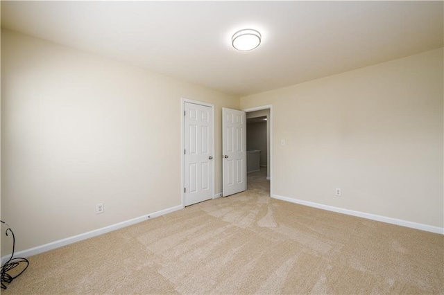 unfurnished bedroom with baseboards, a closet, and light carpet