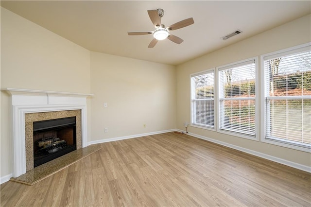 unfurnished living room featuring visible vents, light wood-style floors, a fireplace, baseboards, and ceiling fan